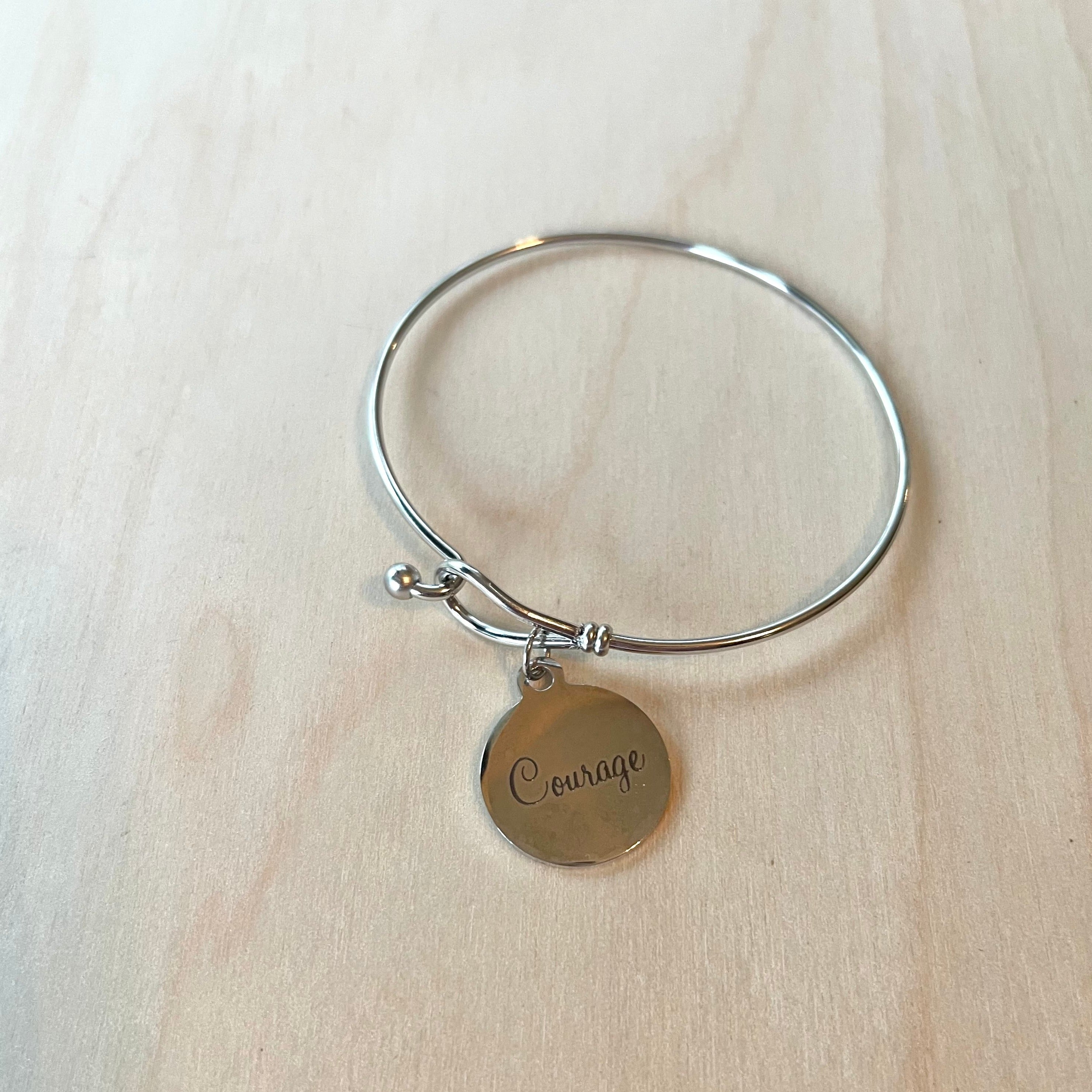 Handcrafted bangle bracelet with charm in stainless steel.  Inner Diameter: 57mm