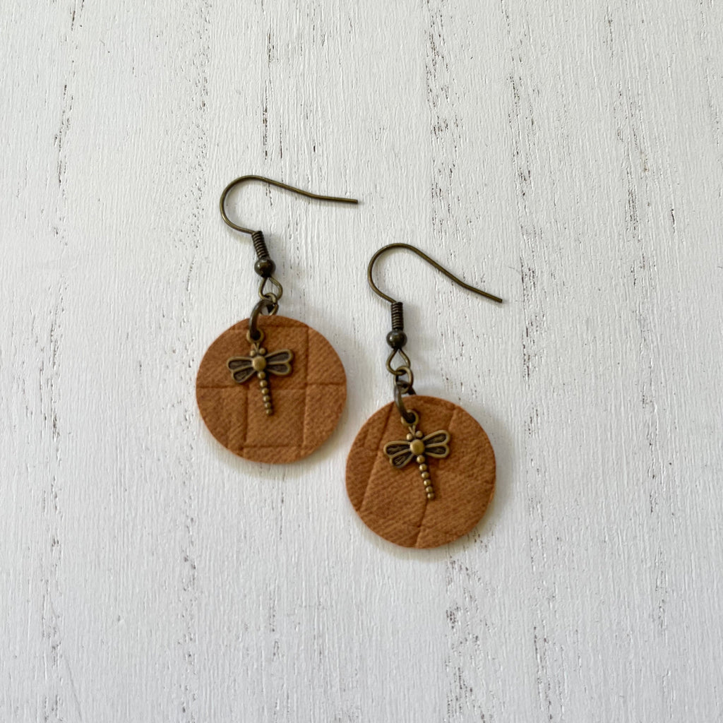 Handcrafted earrings on brass earring wires.  Brass dragonflies on leather circle cut outs.