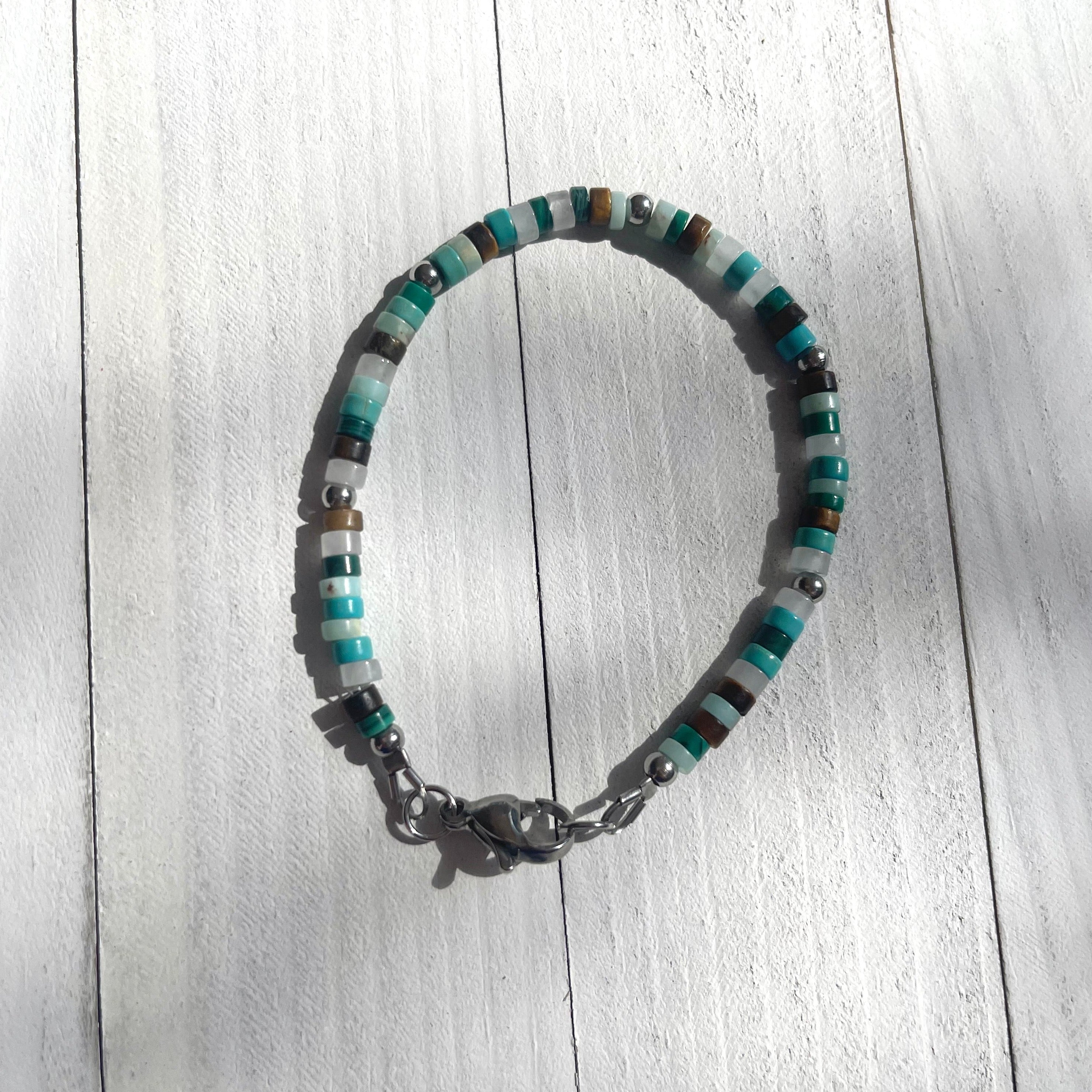 Handcrafted bracelet with stainless steel components. Beaded with tiger eye, howlite, malachite, jasper, quartz, and stainless steel. Measures 8 inches.