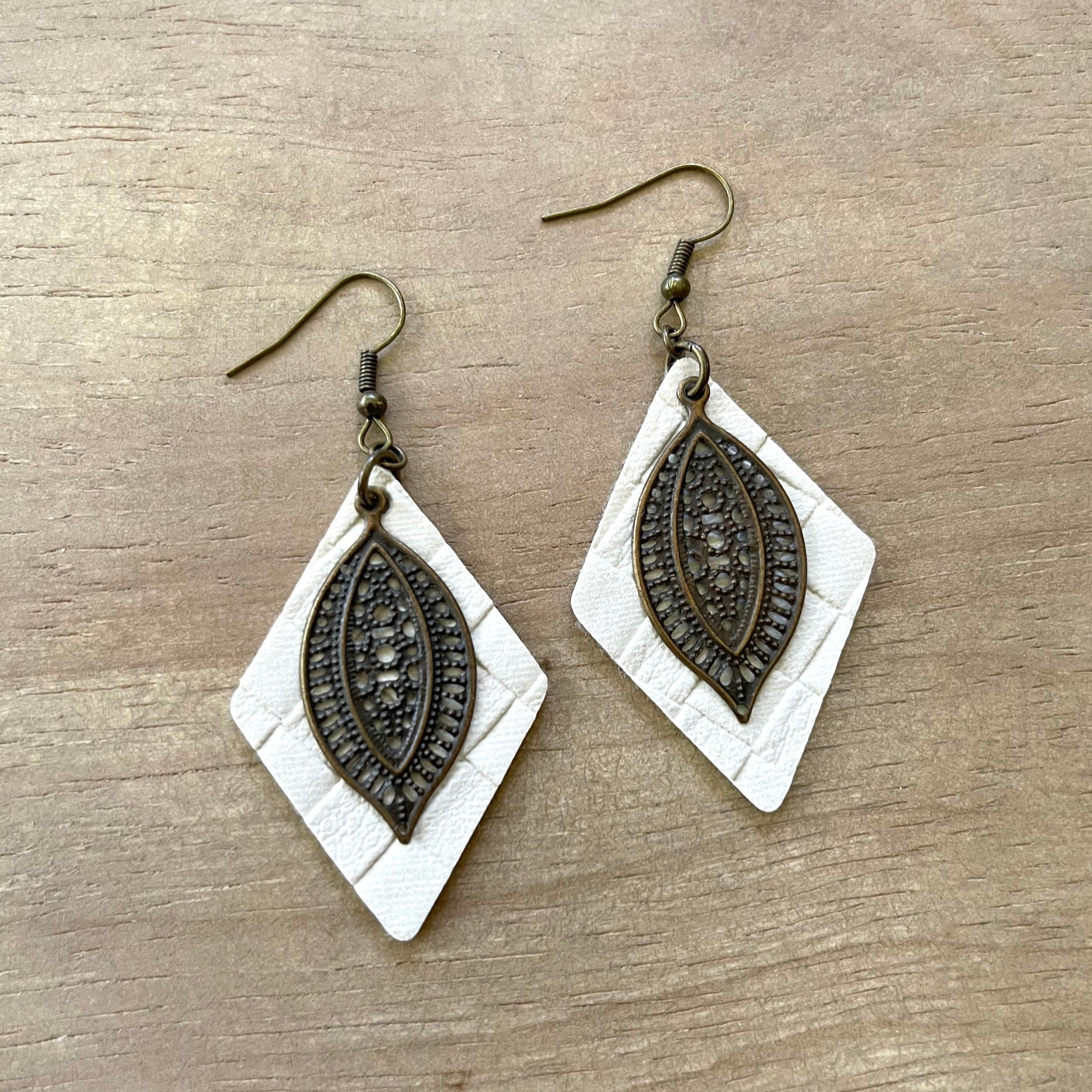 Handcrafted earrings on brass earring wires.  Brass filigree pendants on leather diamond cut outs.