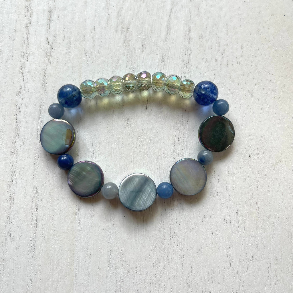 Handcrafted stretch bracelet made with professional strength ninja cord. Beaded with river shell, glass, blueberry quartz, and blue aventurine.