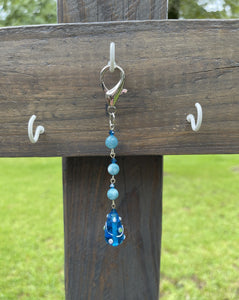 Handcrafted purse charm made with silver 16x30mm lobster clasp. Glass lamp work bead, 8mm blue agate stones, blue bicone crystals. Drop length is 4 5/8 inches.