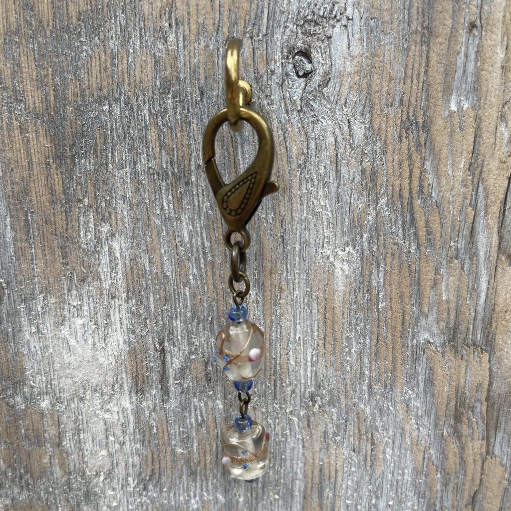 Handcrafted on purse charm on a brass lobster clasp. Glass lamp work beads with Czech glass seed beads to accent. Drop length is 3.25 inches.