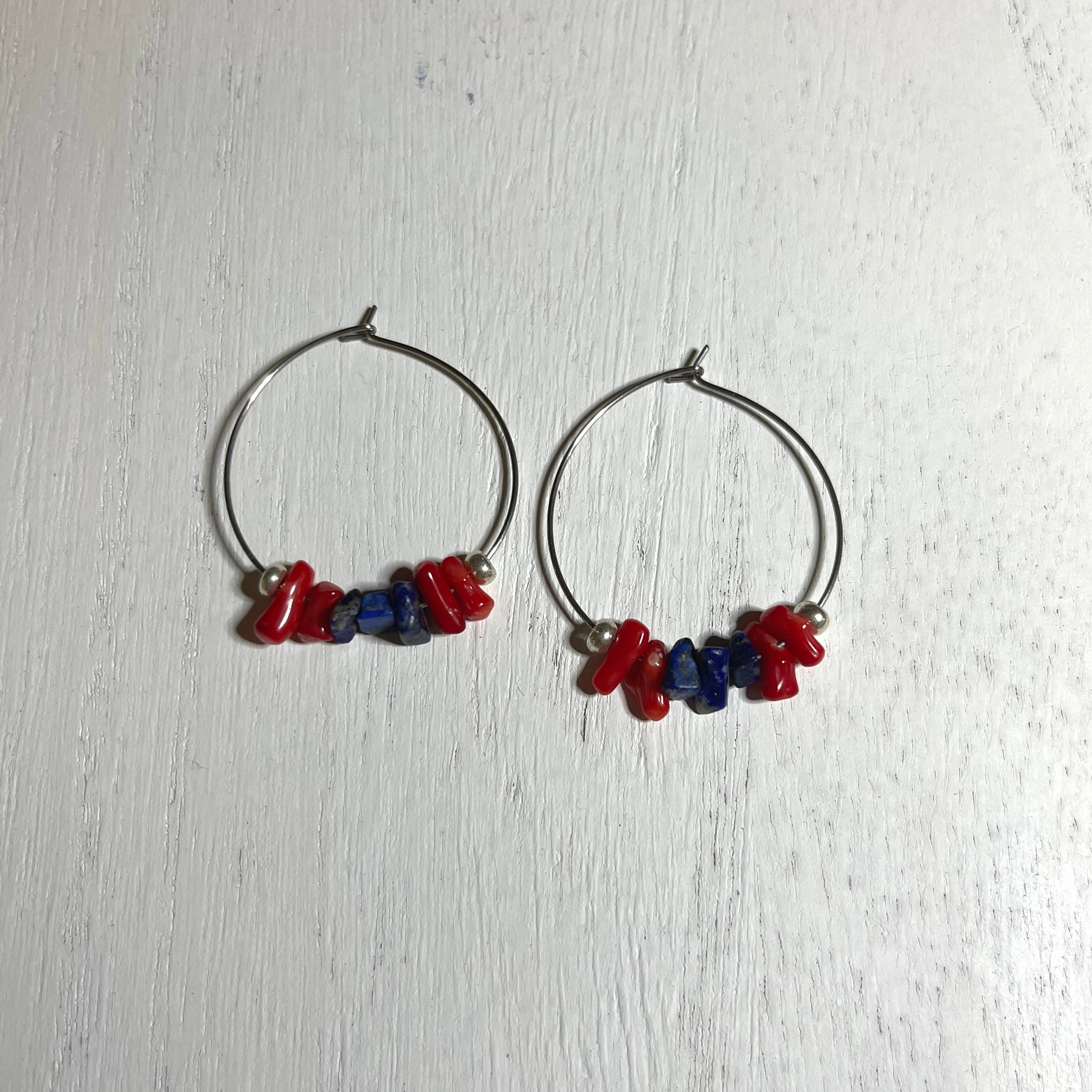 Handcrafted earrings on 35 mm stainless steel hoops. Beaded with lapis lazuli chips, red bamboo coral chips, and silver glass seed accent beads.