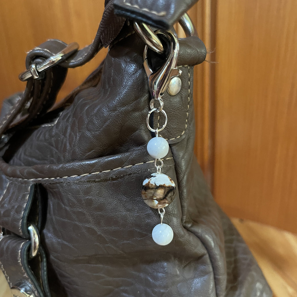 Handcrafted purse charm on a silver plated lobster clasp. Fire crackle amber agate lentil and howlite stones. Drop length is 3.25 inches.