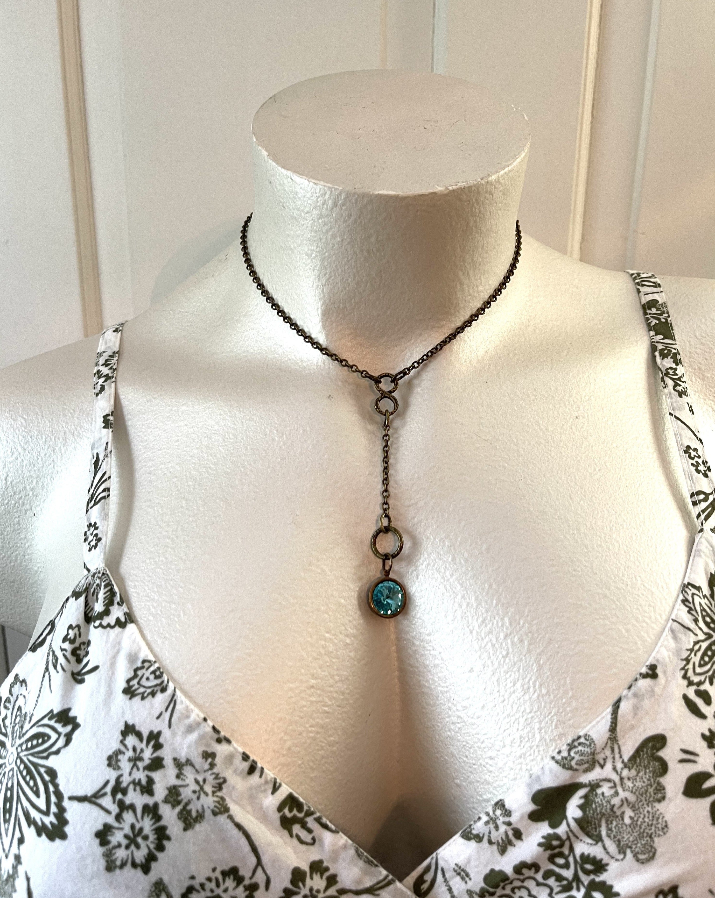 Handcrafted necklace on solid brass chain and components. Blue rivoli rhinestone charm. Necklace is 17 1/2 inches in length with a 4 inch drop.