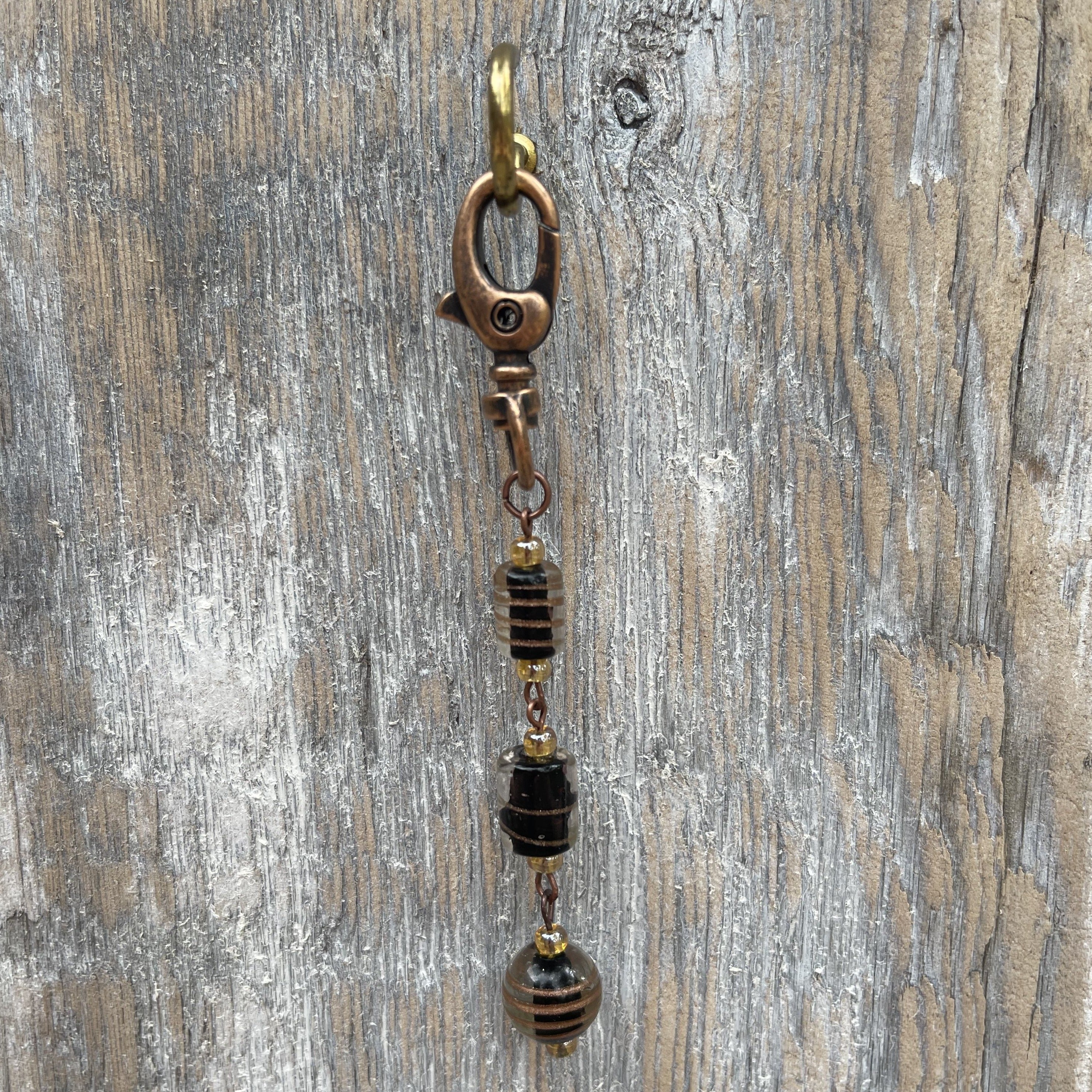 Handcrafted purse charm on an antique copper swivel lobster clasp. Glass lamp work beads and Czech glass beads. Drop length is approximately 4 inches.