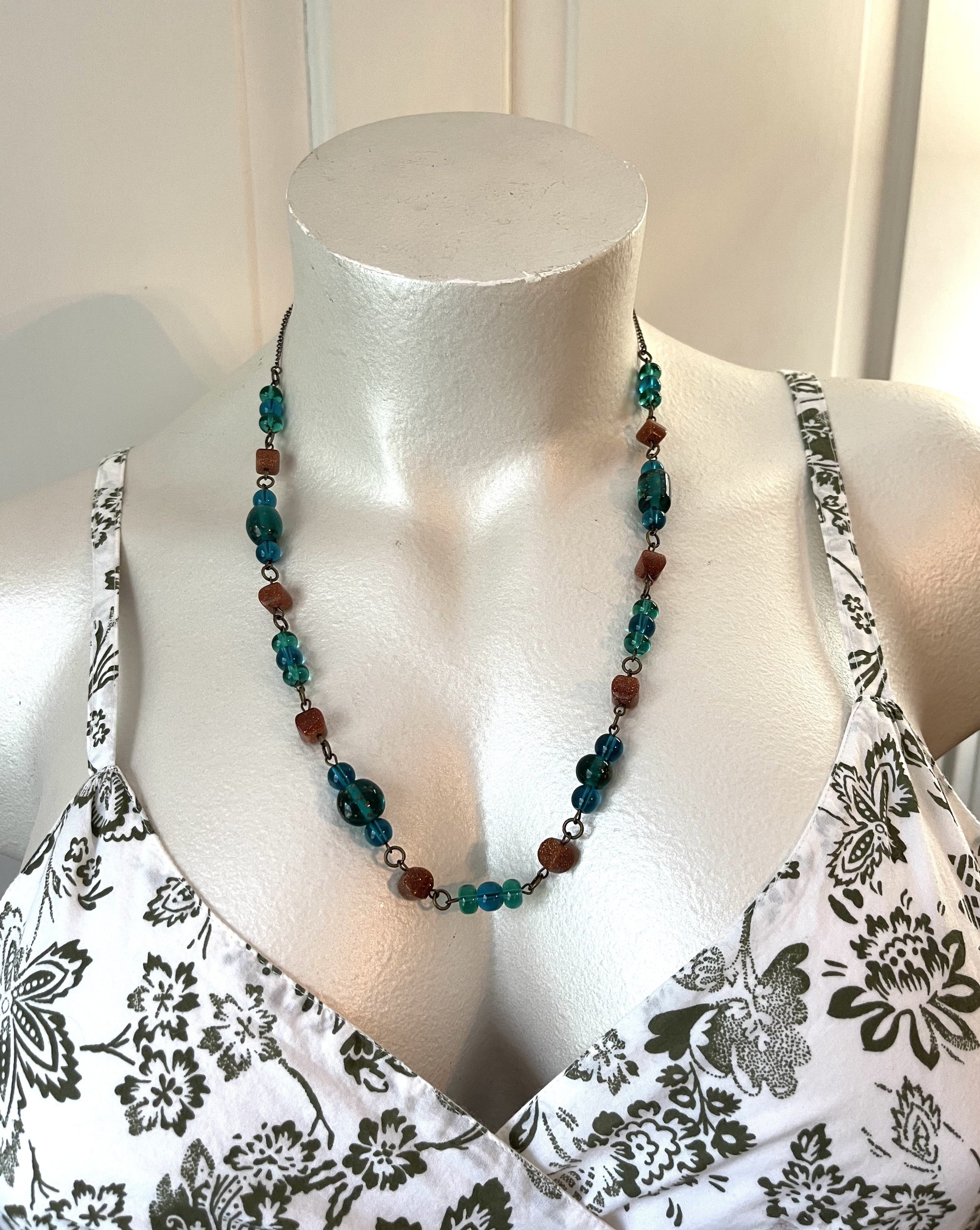 Handcrafted necklace on brass chain and components. Beaded with goldstone cushion beads, and glass. Length is 26 1/4 inches with an 3 1/4 inch extender.