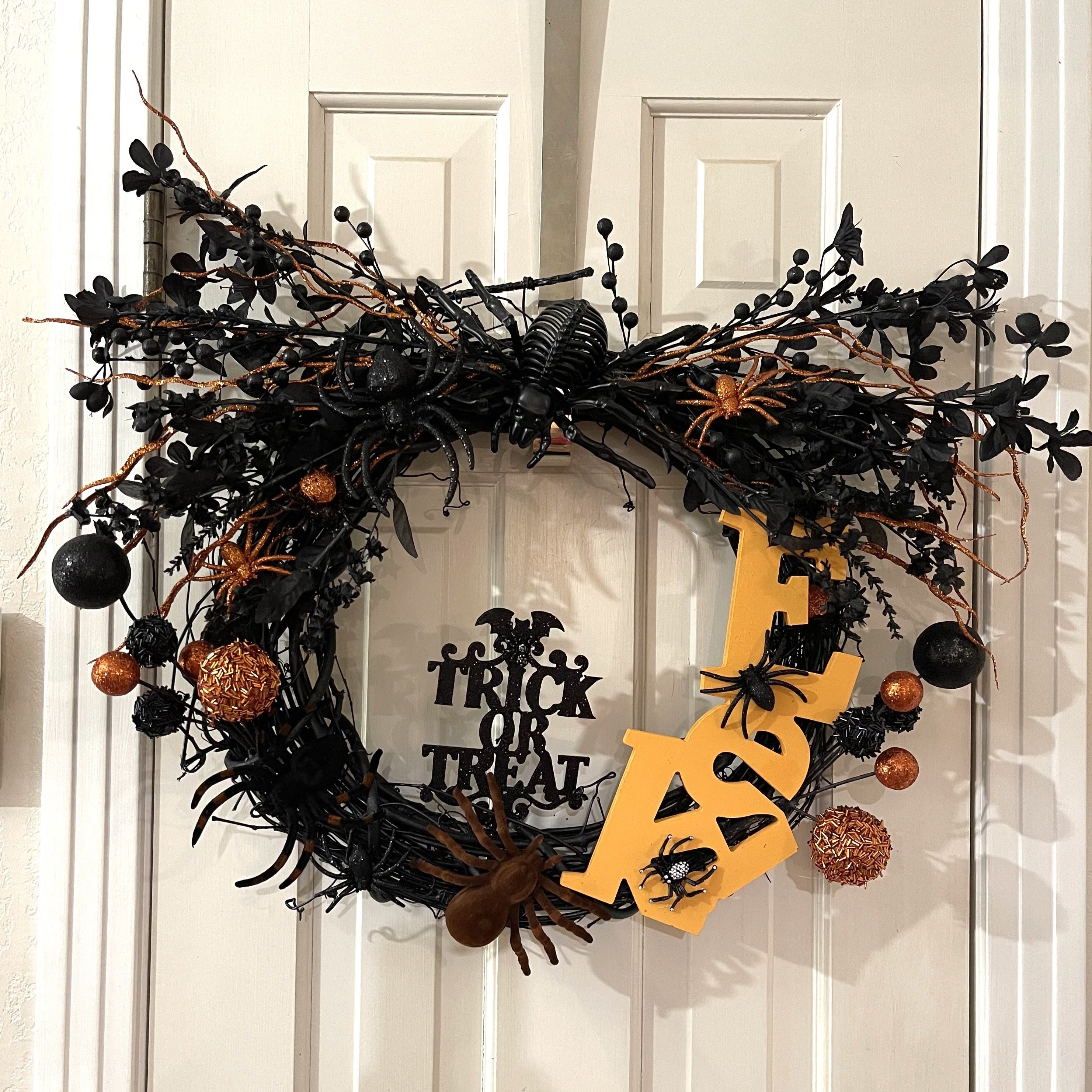 Handcrafted spider wreath on a grapevine wreath base. Wooden "eek" word, florals, and lots of spiders.