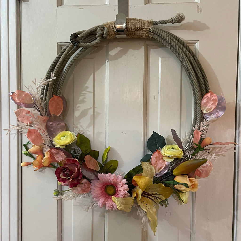 Handcrafted wreath on an upcycled lariat roping rope. Width: Approximately 19 inches. Florals and burlap for decor. 