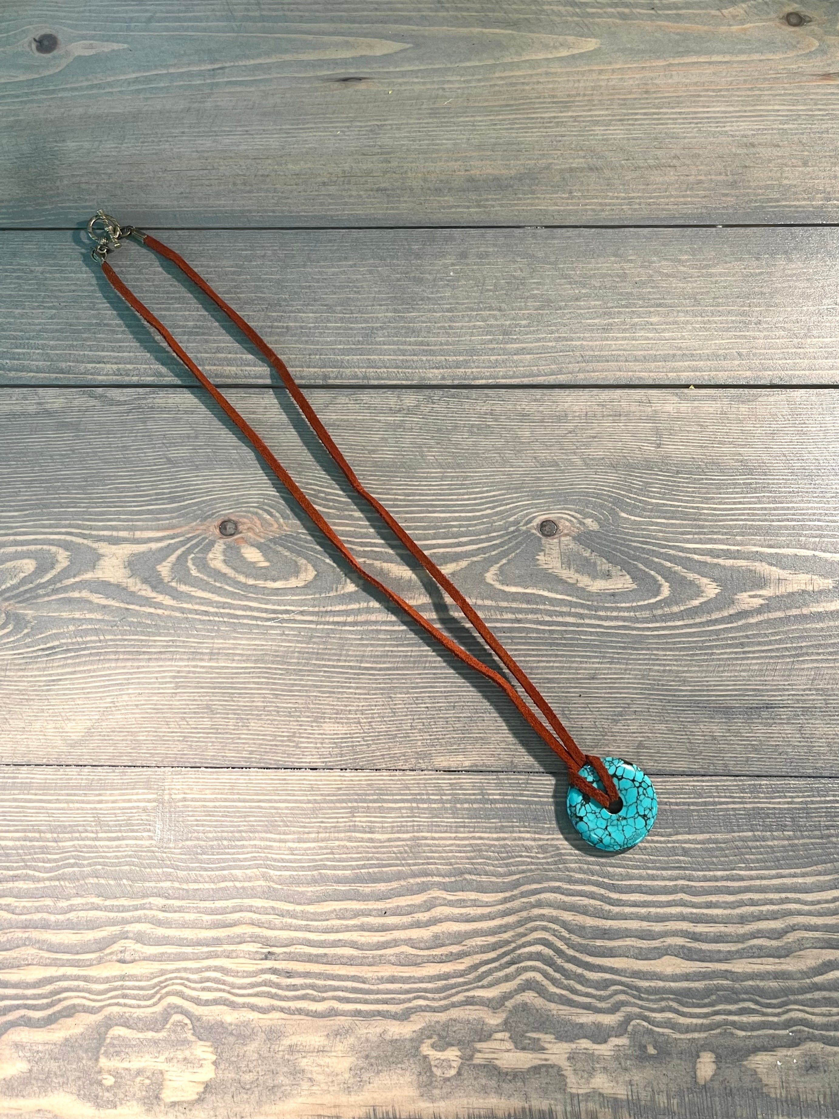 Handcrafted necklace with suede leather cord.  Brass toggle clasp and components. Turquoise pendant. Length: Approximately 22 inches.