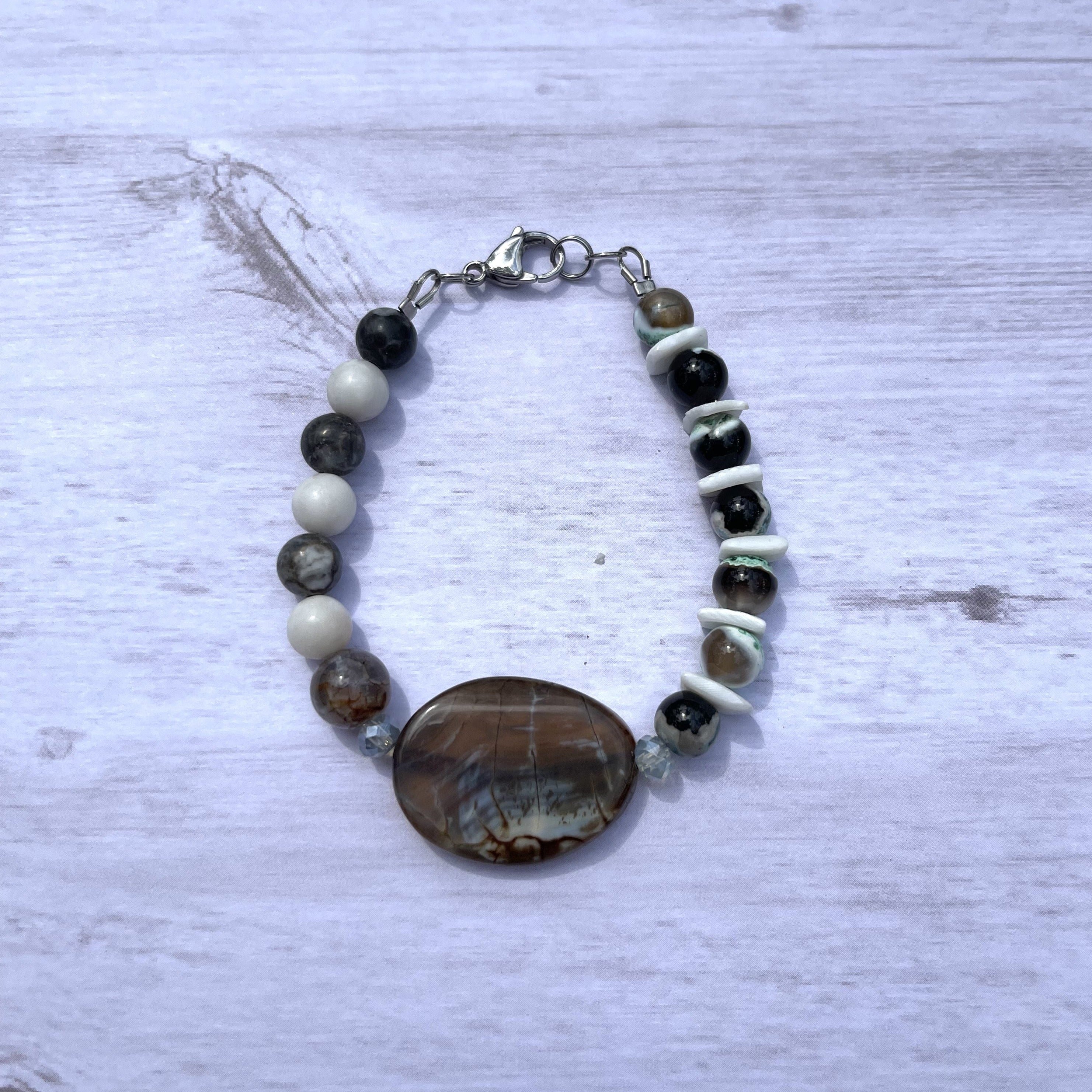 Handcrafted with stainless steel clasp and components. Beaded with light blue crystals, puka shells, green agate stones, zebra jasper stones, and amber crackle agate stones.  Length is 8.25 inches.