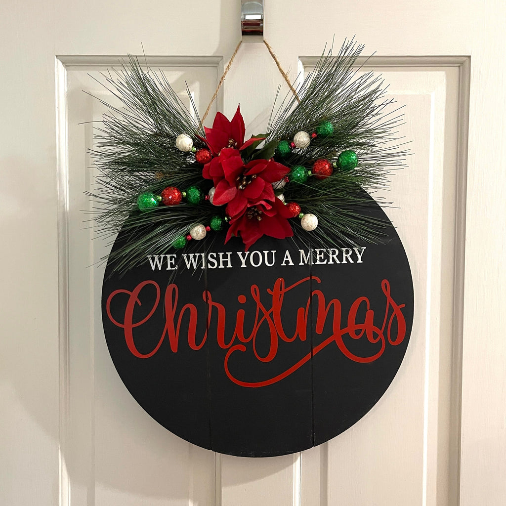 Handcrafted Christmas door hanger on a black shiplap door round. Painted design accented with Christmas florals. 