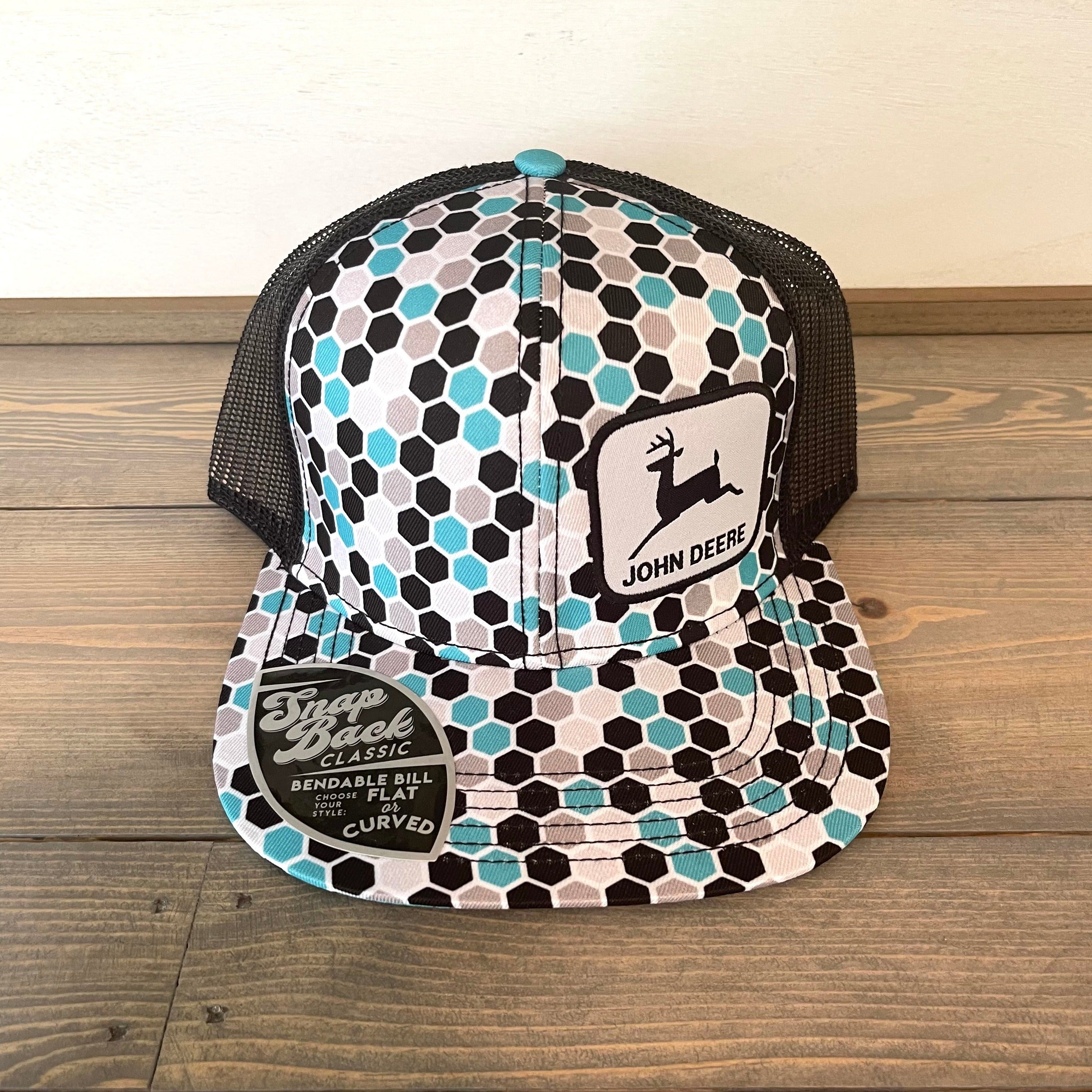 Women's John Deere Cap in turquoise and black. One size fits most. Logo patch on the front. Snap back classic adjustable closure. Bendable bill. Choose your style: flat or curved. Mesh back.