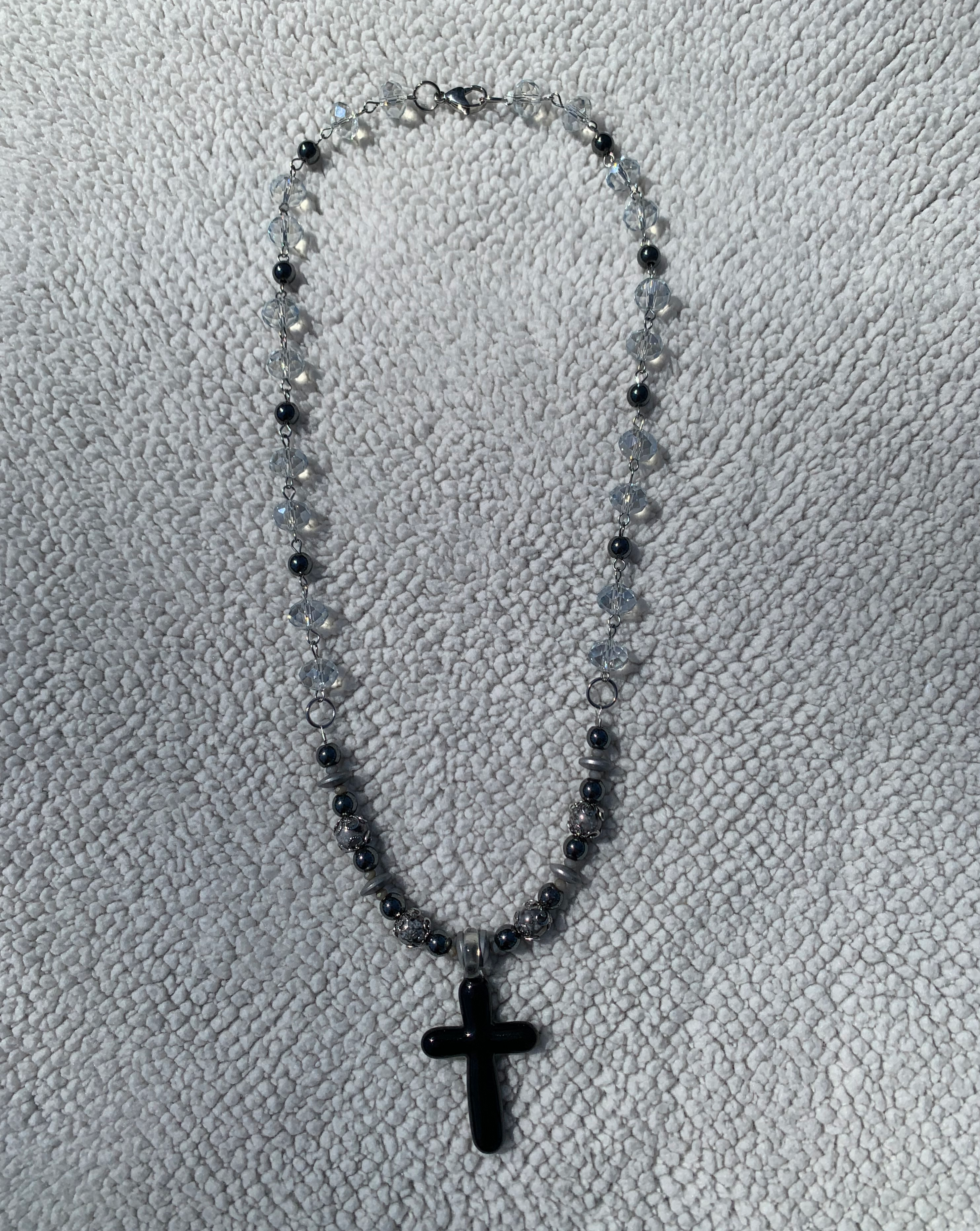 Handcrafted with all stainless steel. Approximately 21 1/2 inches at a matinee length. Glass cross pendant, hematite disk spacers, 6mm black hematite, 8mm gray glass luster beads, glass blue luster rondelles and tiny crystal accent beads.