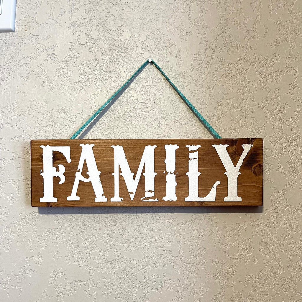 Handcrafted wooden sign with turquoise braided cord for hanging. Length is 12 inches. Painted distressed lettering, stained, and sealed.