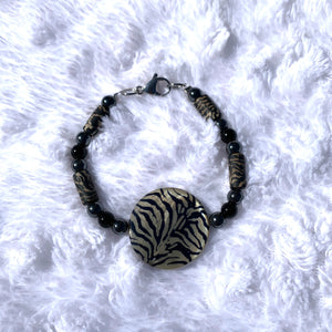 Handcrafted with a zebra shell disk, black glass beads, 6mm black hematite, and zebra clay cylinder beads. Bracelet has a stainless steel lobster clasp. Length is approximately 7 3/4 inches.