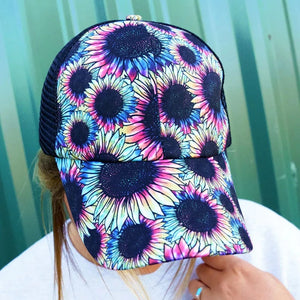 Sunflower prism ponytail cap. 65% Cotton, 35% Polyester. Print front. Black mesh back. Slot with criss-crossing elastic bands in back for high ponytail or bun. 7 panel - 2 solid, 4 mesh, and 1 with straps and closure. Adjustable velcro closure. Button top. Pre-curved visor. Adjustable, One Size Fits Most.